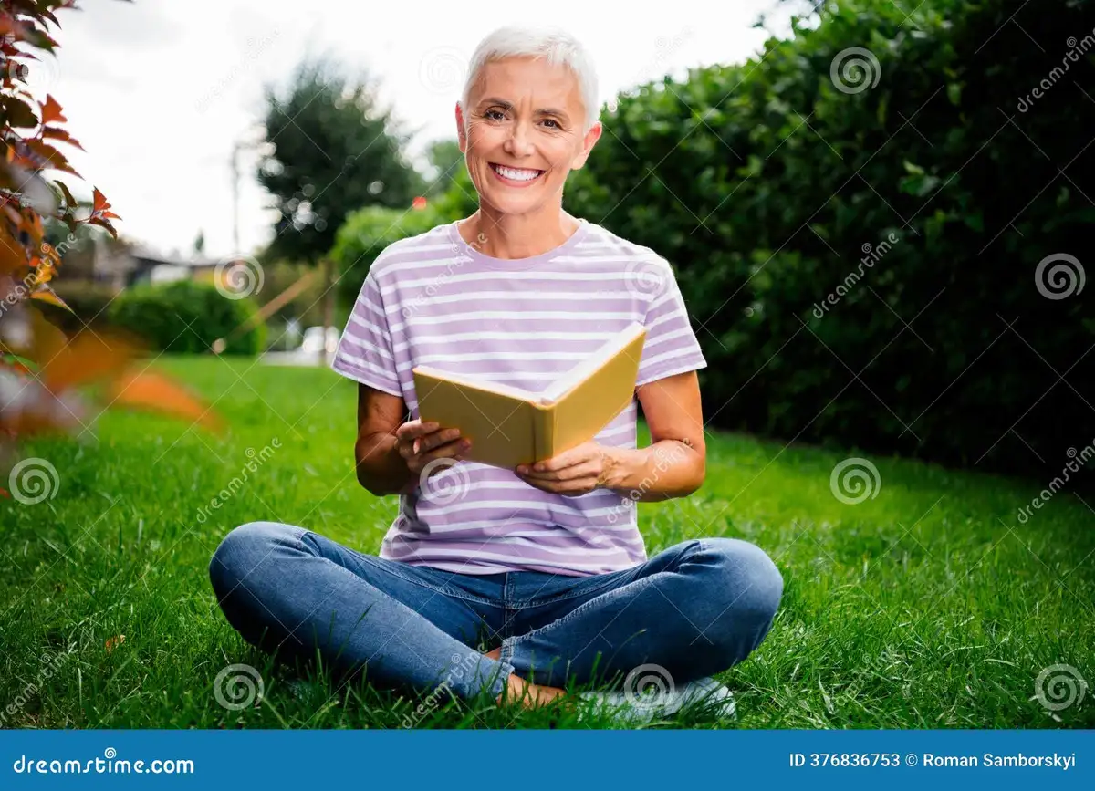 elderly woman sitting peacefully in a park with a book summer